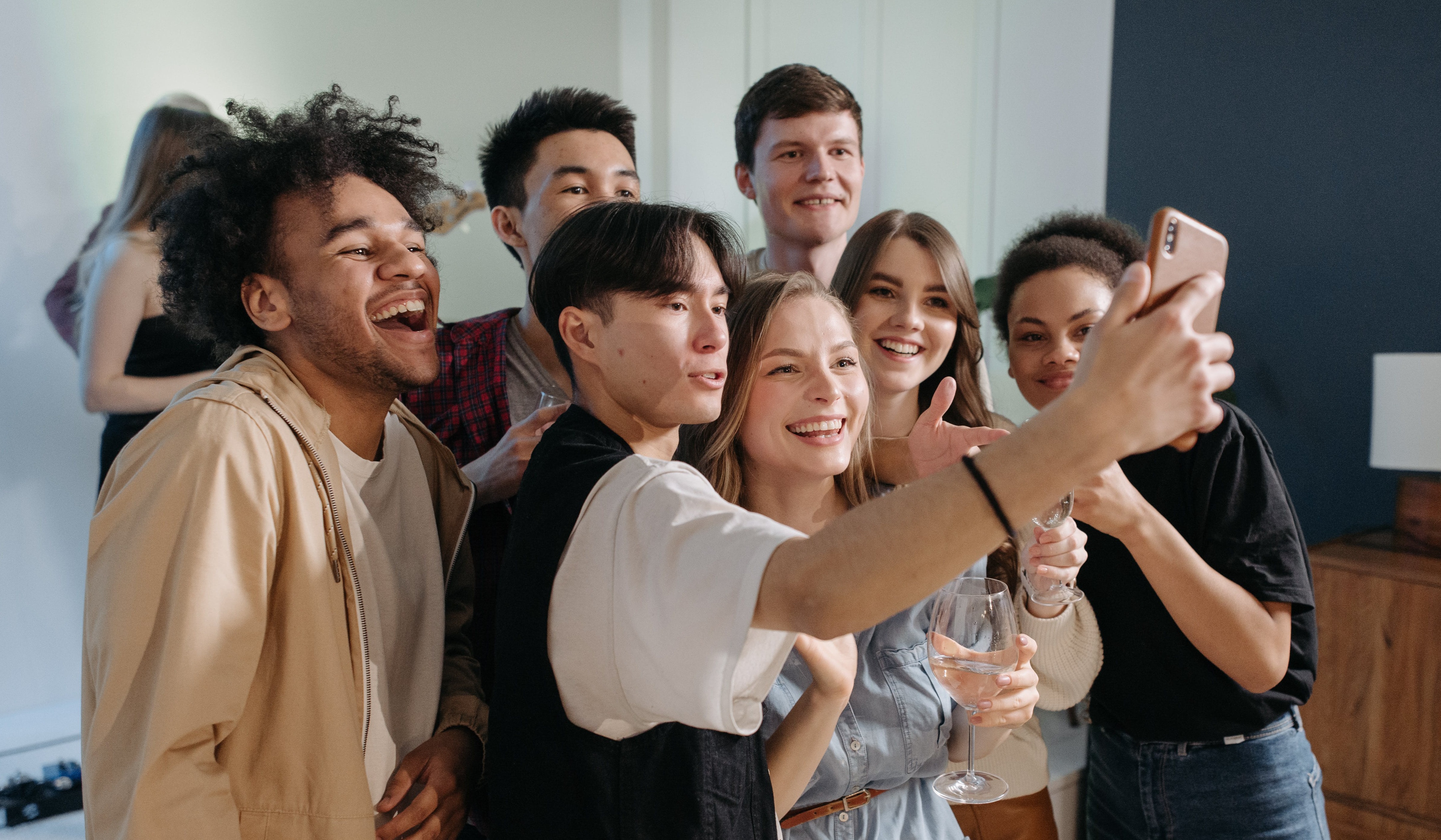 A wide shot of a smiling group selfie taken indoors.