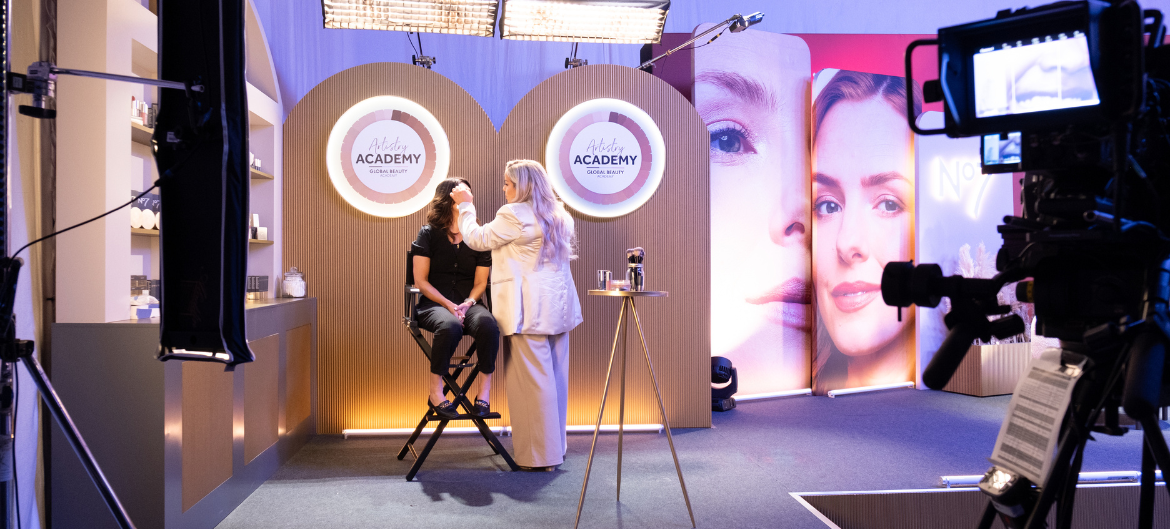 Wide shot of a make up artist putting on a customer's makeup at the No 7 Virtual Training Event