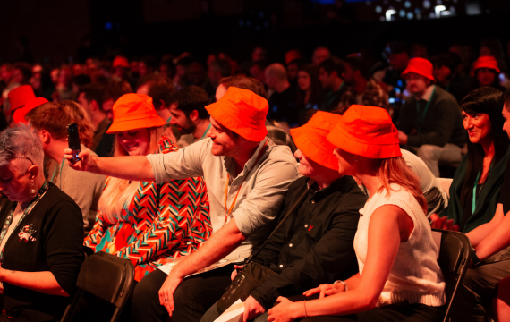 Shot of a group of people taking a selfie wearing orange bucket hats.