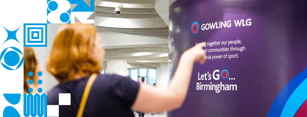 Woman with short red hair pointing Gowling WLG branding, left of the photo mix of white and light blue square that make up DRPG branding