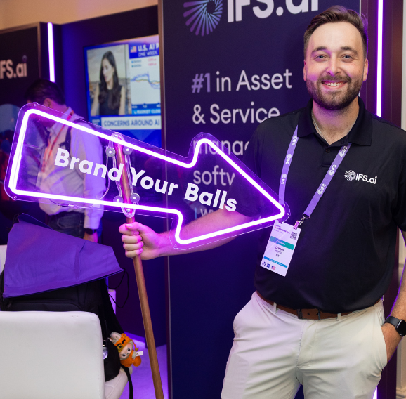 Shot of someone holding a 'Brand Your Balls' sign at the international IFS exhibition stands that DRPG created.
