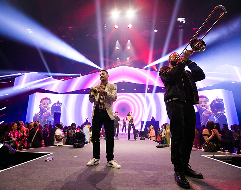 Band on stage with brass instruments surrounded by crowd of people